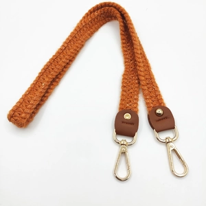 Detail of hand-knit crochet shoulder strap with brown leather ends and gold metal clasps