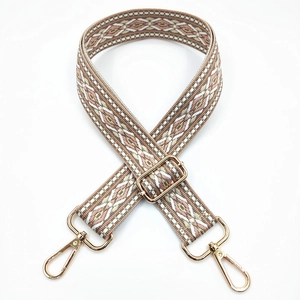 Close-up of geometric jacquard embroidered bag strap with golden metal hardware