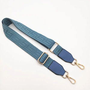 Macro view of blue maze pattern woven bag strap with golden metal hook details