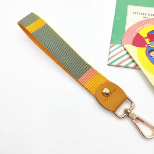 Detail of colorful woven hand strap with gold metal lobster clasp and yellow leather trim