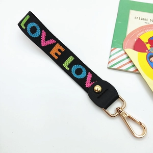 Close-up of black webbing strap with rainbow LOVE letters and gold lobster clasp