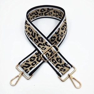 Adjustable leopard print bag strap with gold metal hardware and black white striped edges