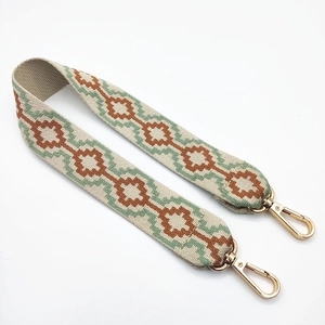 Close-up of geometric jacquard woven strap with light gold swivel metal buckles