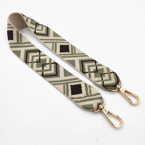 Detail of ethnic geometric woven bag strap in vintage green with gold metal clasps