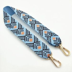 Detail of wide ethnic style woven bag strap with blue geometric patterns and gold clips