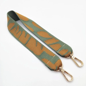 Macro detail of ethnic green leopard print bag strap with polished gold metal lobster clasps