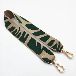 Close-up of bohemian woven bag strap with green leaf pattern and gold metal lobster clasps
