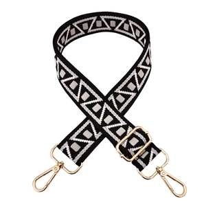Close-up of black and white geometric woven strap with gold metal lobster clasps