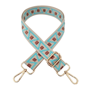 Detail view of adjustable ethnic style bag strap with blue geometric patterns and gold clips