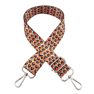 Detail of adjustable woven shoulder strap with orange and grey fish scale patterns and silver buckle