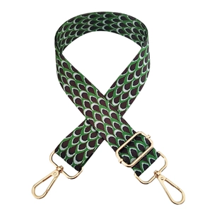 Detail of adjustable peacock pattern bag strap with golden metal hooks and buckles