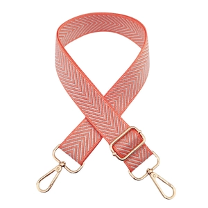 Detail of coral pink herringbone woven bag strap with adjustable pale gold metal buckles