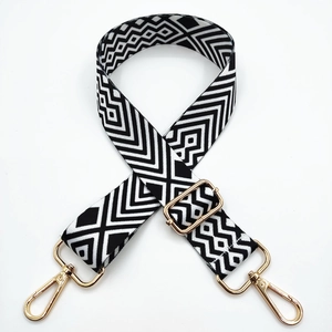 Detail of adjustable black and white geometric wide shoulder strap with gold metal hooks