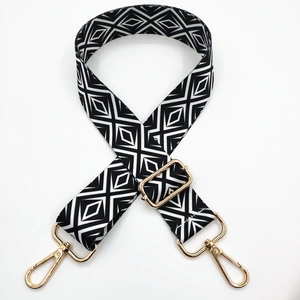 Detail of black and white geometric diamond pattern bag strap with gold lobster clasps