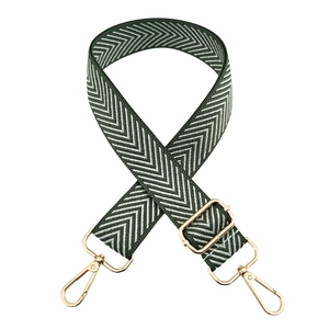 Macro detail of dark green herringbone woven bag strap with glossy gold lobster clasps