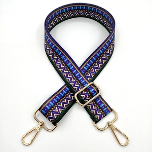 Close-up of geometric ethnic bag strap with purple patterns and gold metal lobster clasps