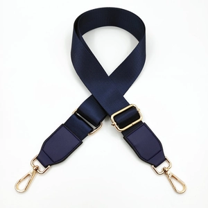 Detail of navy nylon bag strap with gold lobster clasps and leather reinforcement