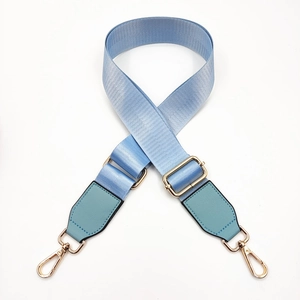 Detail of light blue nylon bag strap with gold metal hardware and green leather reinforcement