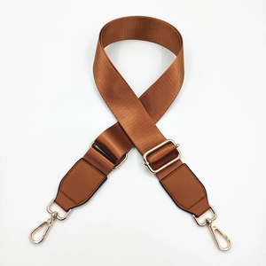 Macro shot of nylon bag strap with brown leather ends and gold metal rotating hooks