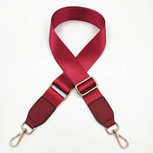 Close-up of wine red adjustable nylon bag strap with gold metal hooks and leather ends
