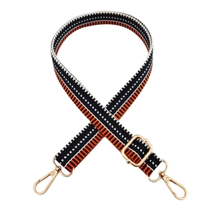Close-up of geometric orange and black woven bag strap with adjustable gold metal buckle