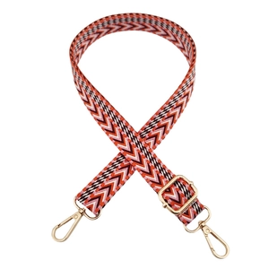 Close-up of ethnic weave 2.5cm adjustable bag strap with red wave pattern and gold hardware