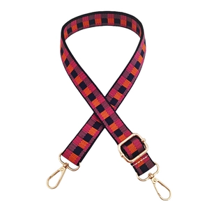 Detail of adjustable plaid canvas strap with gold metal lobster clasps and buckle