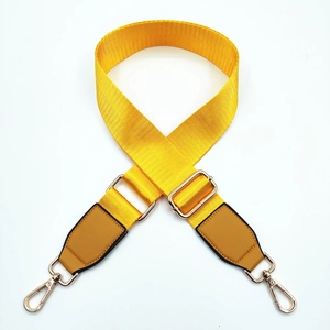 Close-up of adjustable bright yellow nylon bag strap with gold metal hooks and leather