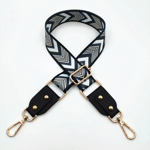Detail of adjustable bag strap with black and white chevron pattern and gold metal hooks