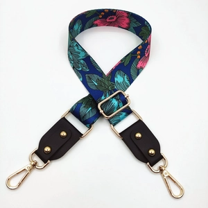 Detail of adjustable floral bag strap with gold metal hardware and brown leather