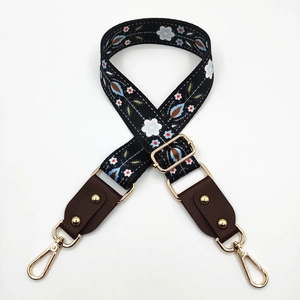Detail of adjustable floral bag strap with gold rivets and swiveling lobster clasps
