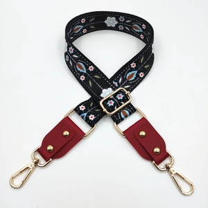Detail of adjustable floral embroidery bag strap with leather ends and golden metal hooks