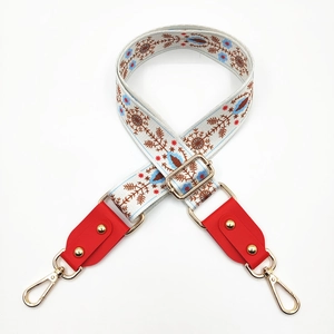 Detail of embroidered floral bag strap with red leather ends and gold metal studs