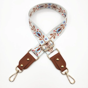 Close-up of ethnic embroidered bag strap with blue floral patterns and gold hardware