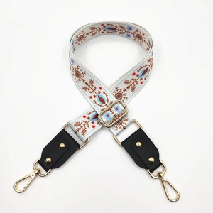 Detail of bohemian wide bag strap with colorful floral embroidery and gold metal rivets