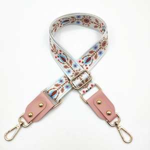 Detail of adjustable floral embroidery bag strap with gold lobster clasps and rivets