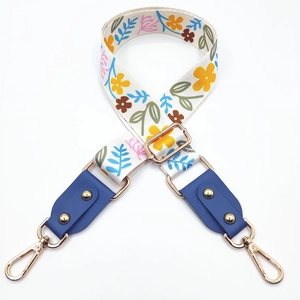 Detail of adjustable floral woven strap with blue leather ends and gold metal clasps