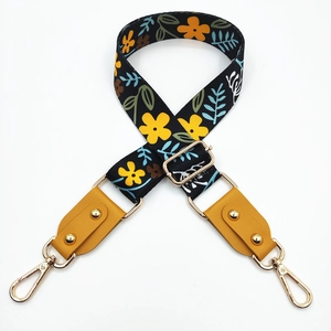 Detail of adjustable floral bag strap with mustard leather ends and gold metal hooks