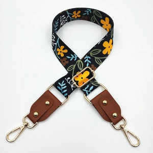Close-up of floral print bag strap with gold rivets and leather connectors