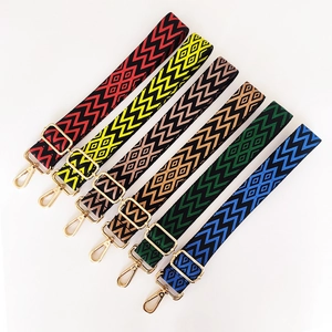 Close-up of adjustable embroidered jacquard bag straps with gold metal hooks and geometric patterns