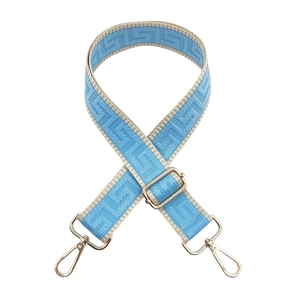Detail of adjustable maze pattern bag strap with gold metal hooks and blue weaving