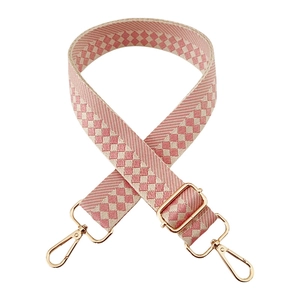 Close-up of pink and cream checkerboard jacquard wide bag strap with gold metal hooks