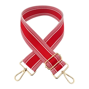 Detail of red 5cm wide bag strap with white stripes and adjustable gold metal buckle