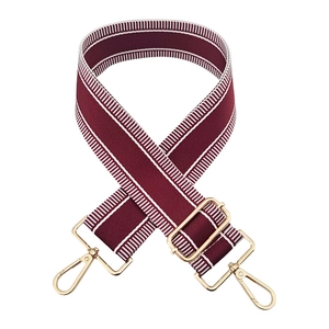 Close-up of wine red woven wide bag strap with white stripes and gold lobster hooks