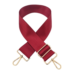 Detail of adjustable burgundy nylon strap with herringbone texture and gold hardware
