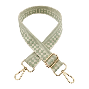 Detail of adjustable sage green and beige checkered canvas strap with gold hardware