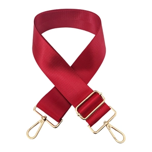 Close-up of red nylon bag strap featuring herringbone weave and gold metal hardware