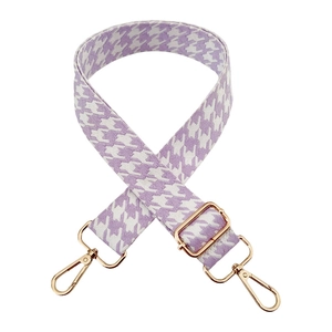 Detail of purple and white houndstooth jacquard shoulder strap with gold metal buckles