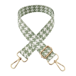 Detail of adjustable green houndstooth jacquard bag strap with gold metal buckles