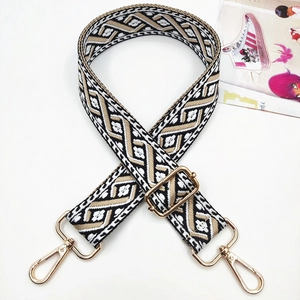 Close-up of geometric jacquard bag strap with gold metal lobster hooks and adjustable buckle